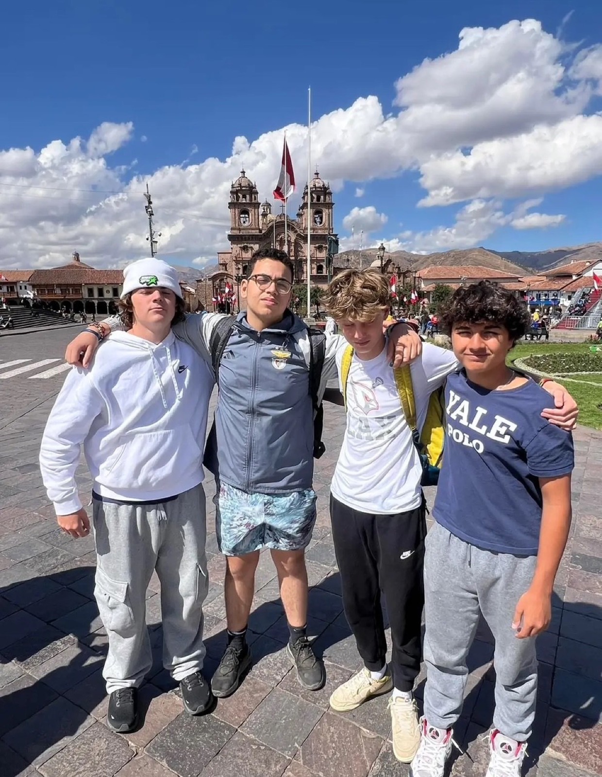Four students posing in a plaza in Cusco with a historic church behind them