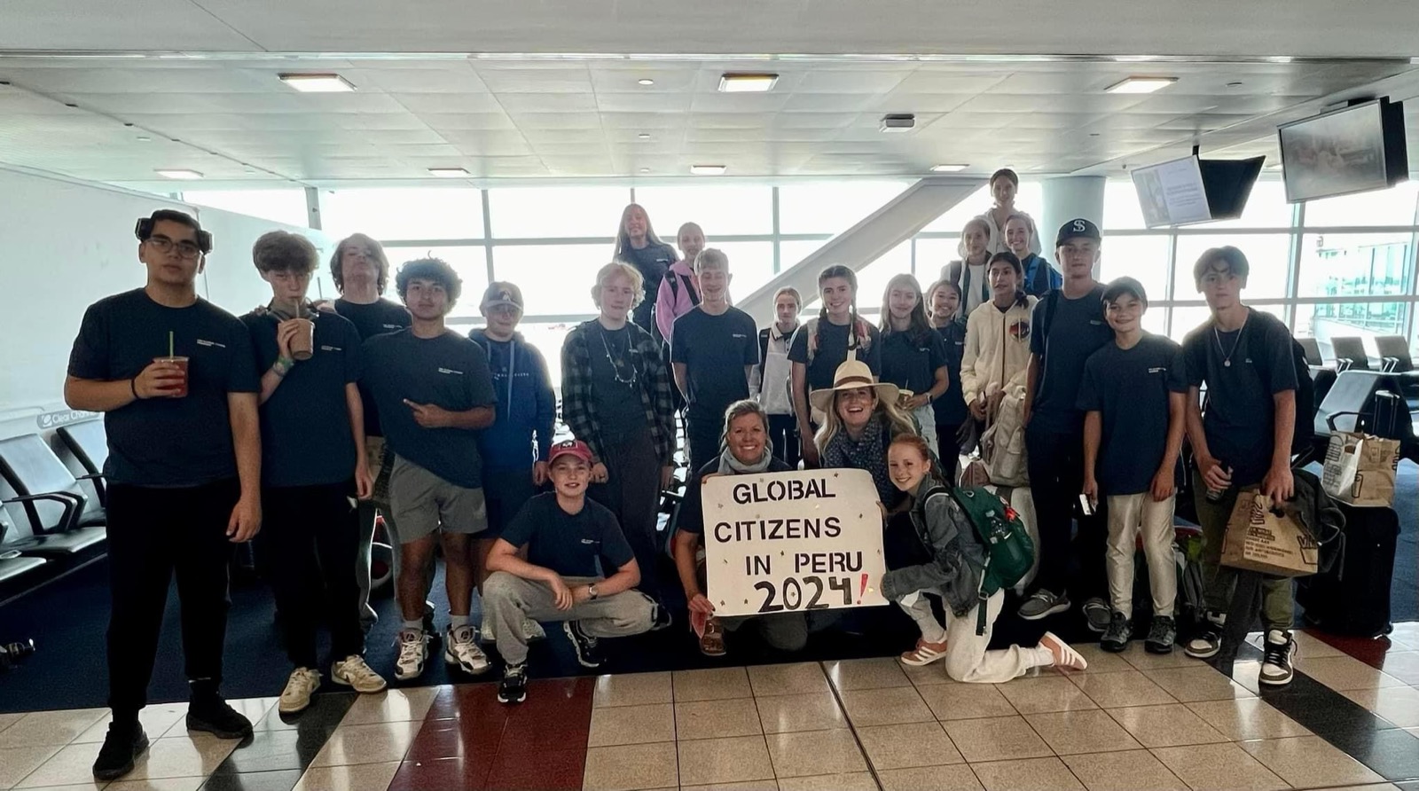 The Global Citizens group at the airport holding a sign reading Global Citizens in Peru 2024